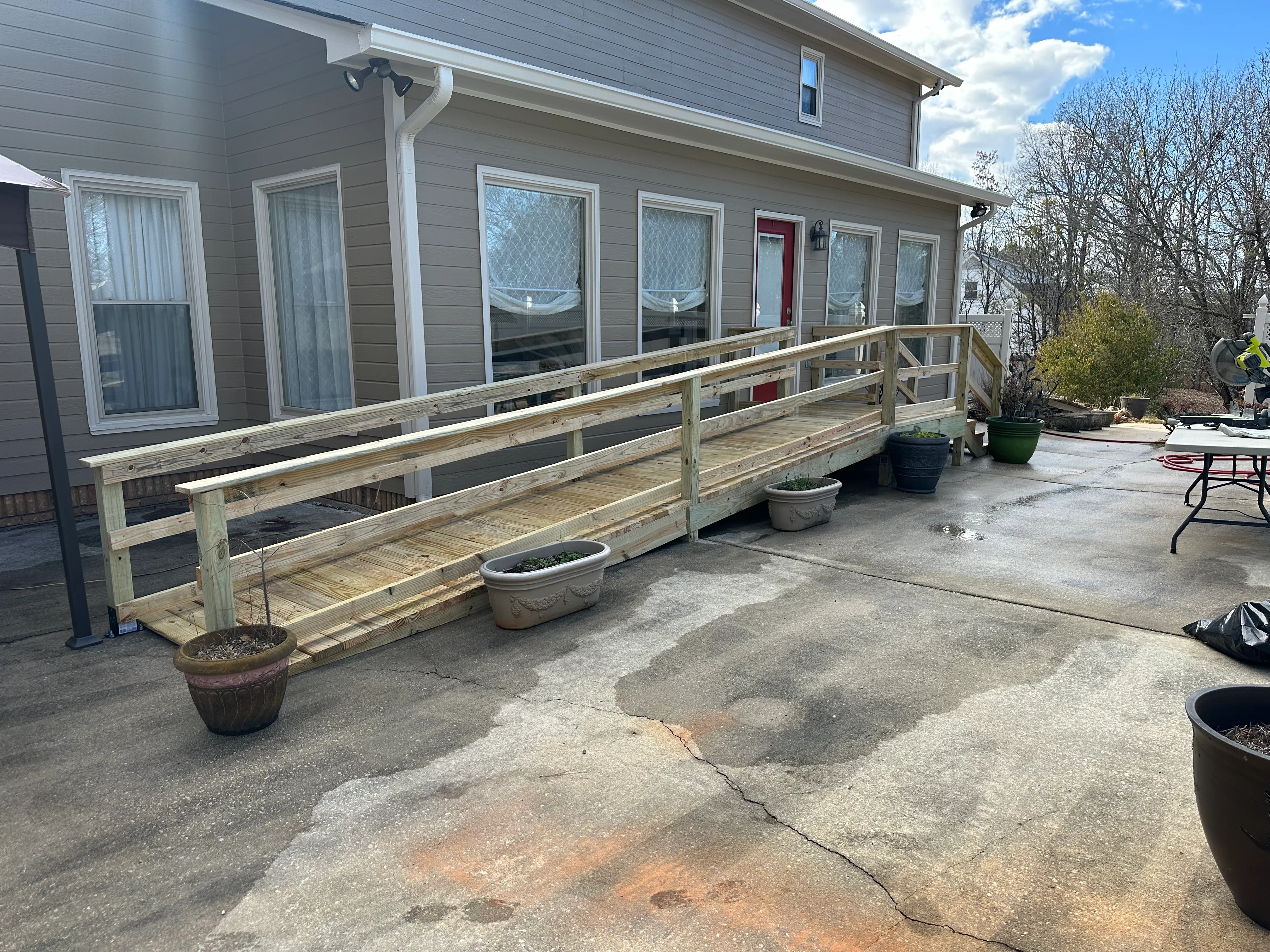 New wooden deck with railings attached to gray house with multiple windows