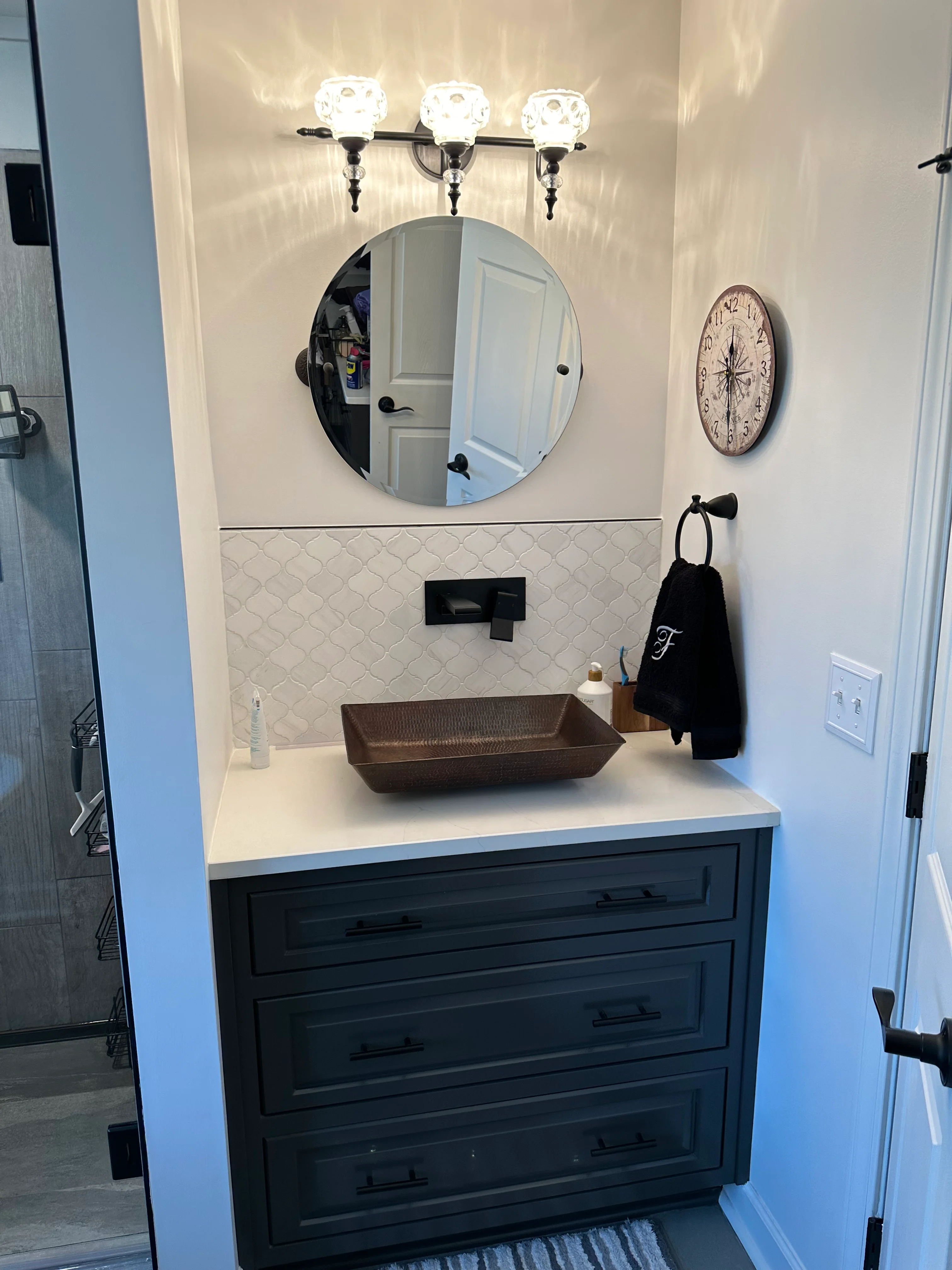 Modern bathroom vanity with dark blue cabinets, white countertop, and geometric tile backsplash