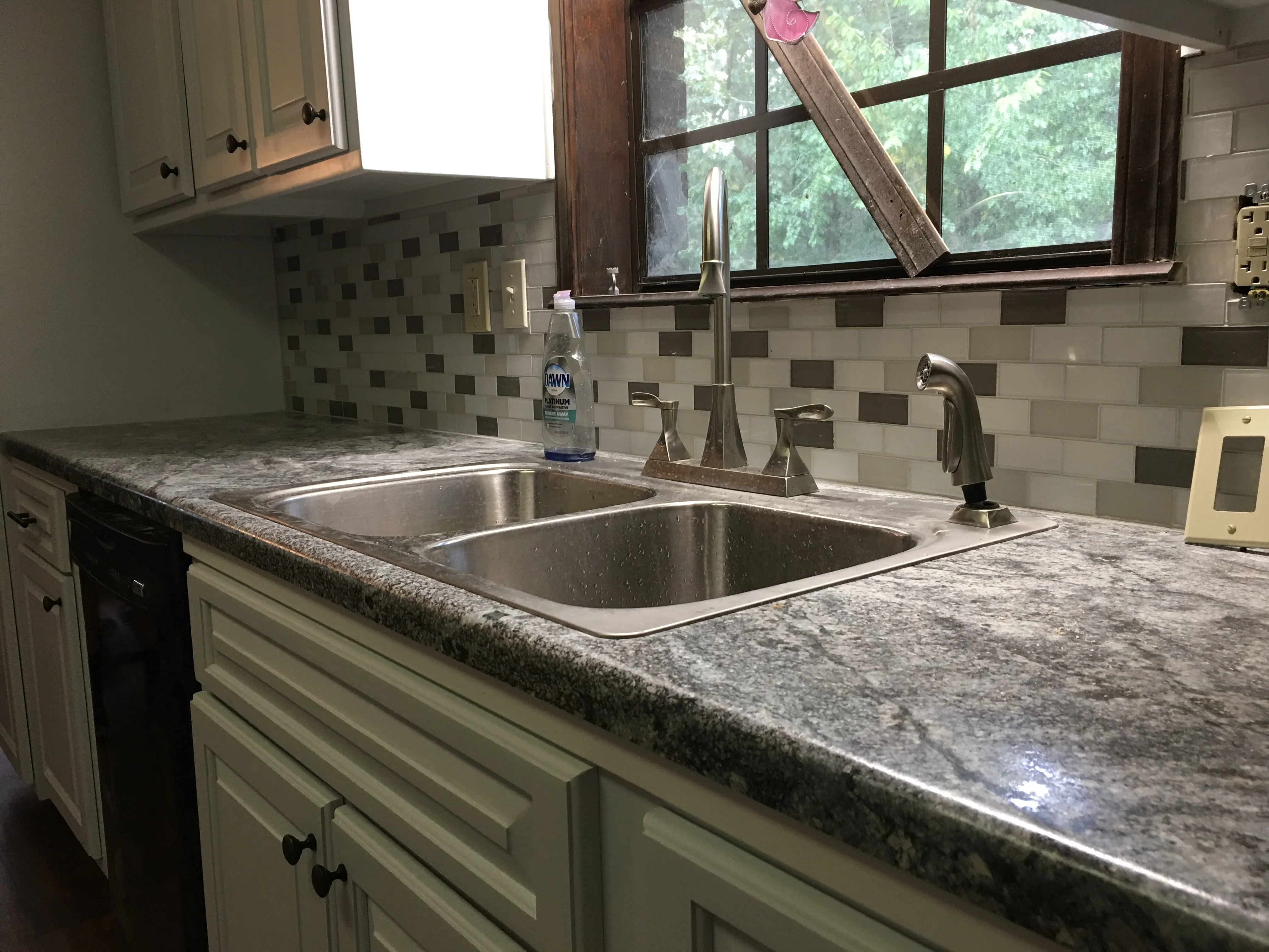 Kitchen sink with granite countertop, double basin, and mosaic tile backsplash