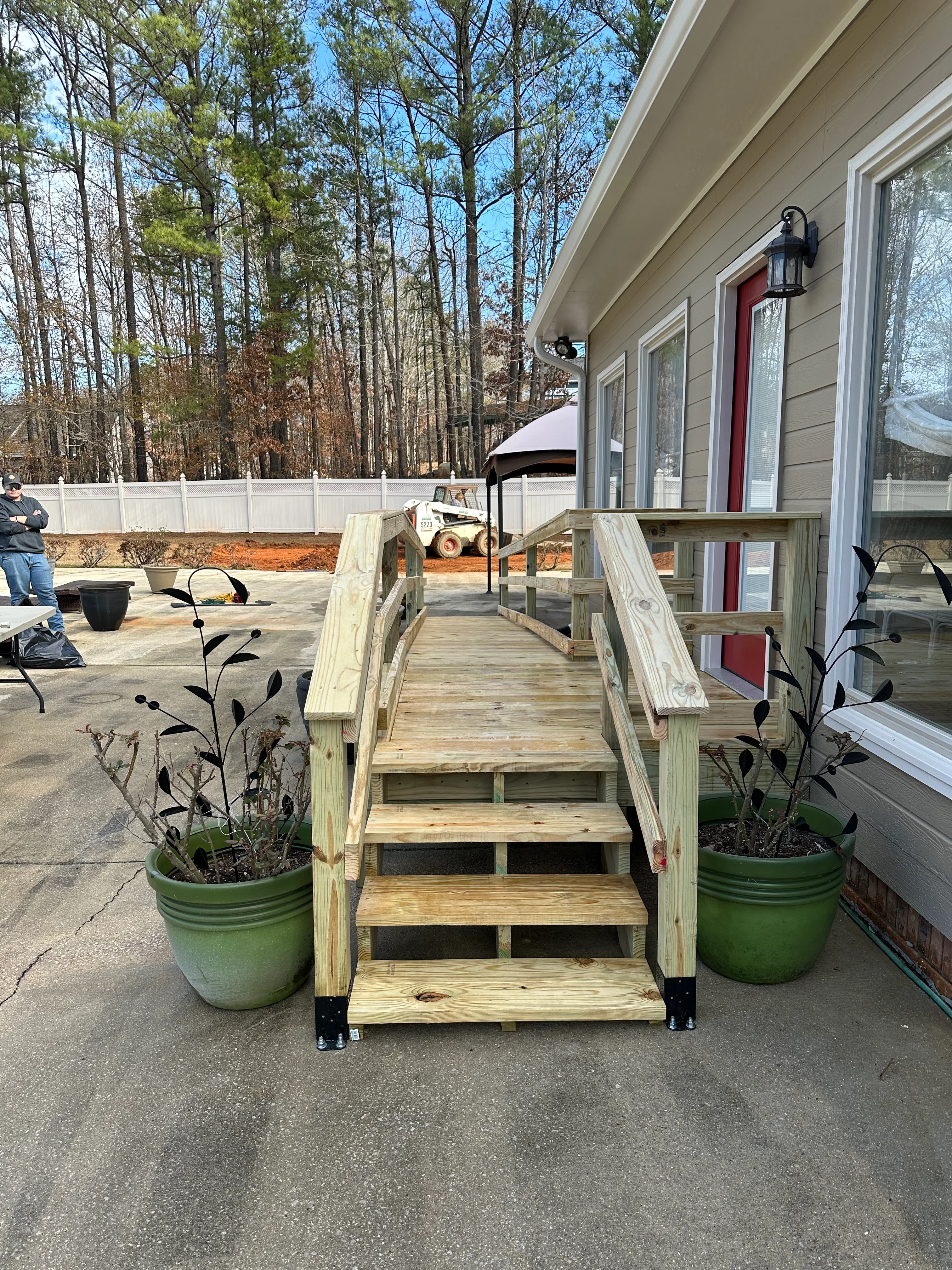 Wooden deck with accessibility ramp and dual handrails leading to home entrance