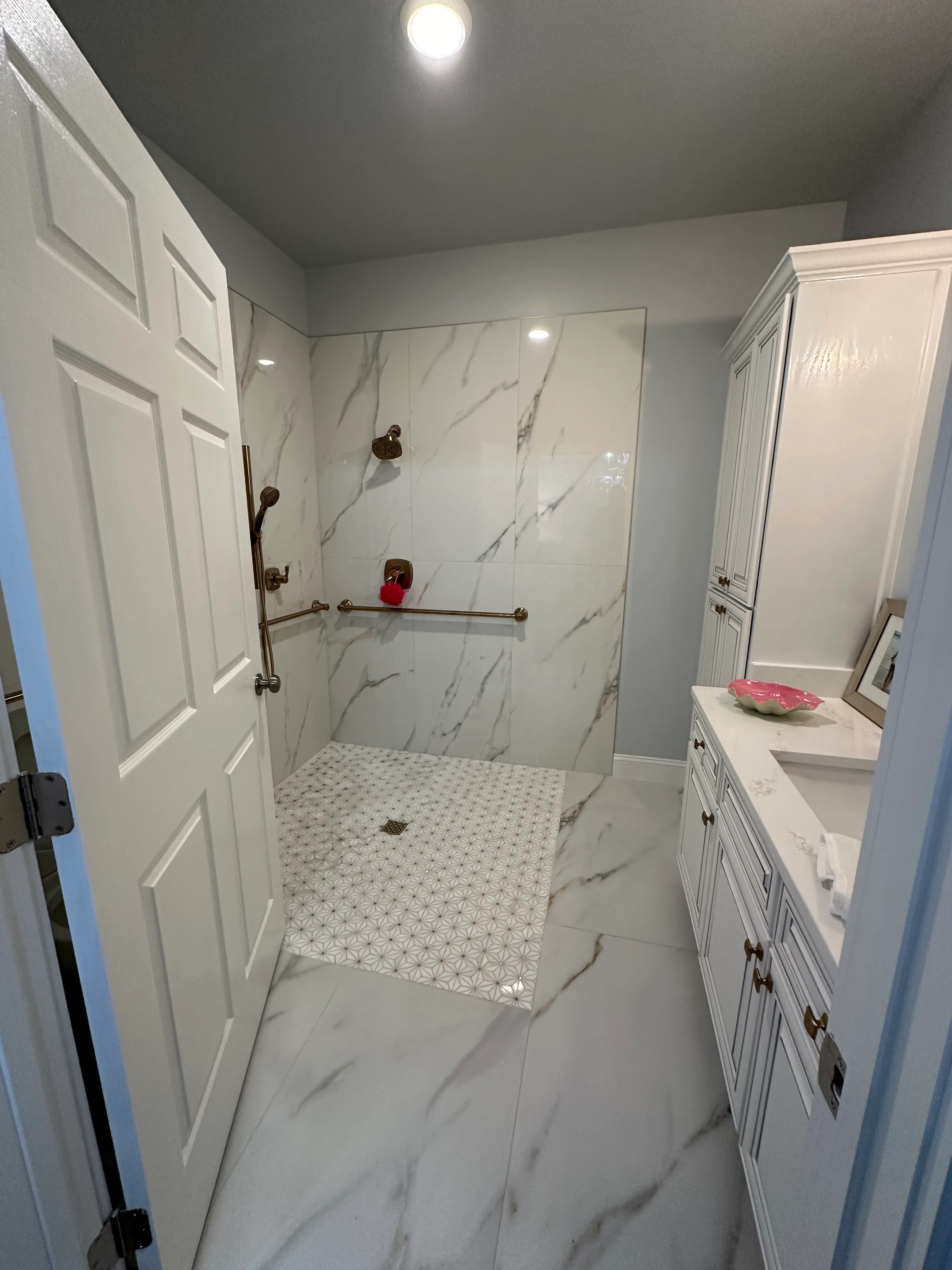 Modern bathroom with marble shower, white vanity, and geometric floor tile