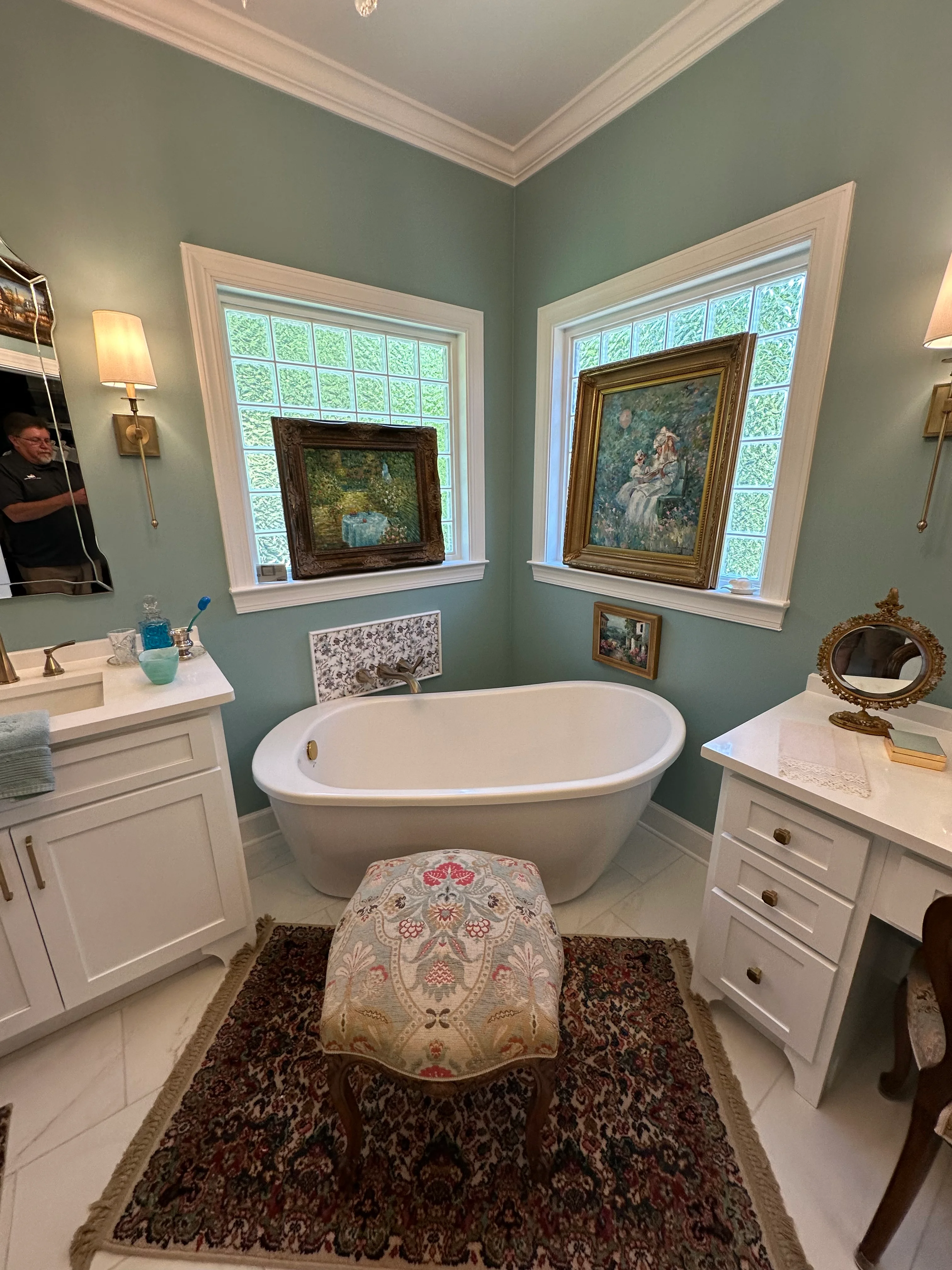 Master bathroom with freestanding tub, sage walls, white vanities, and picture windows