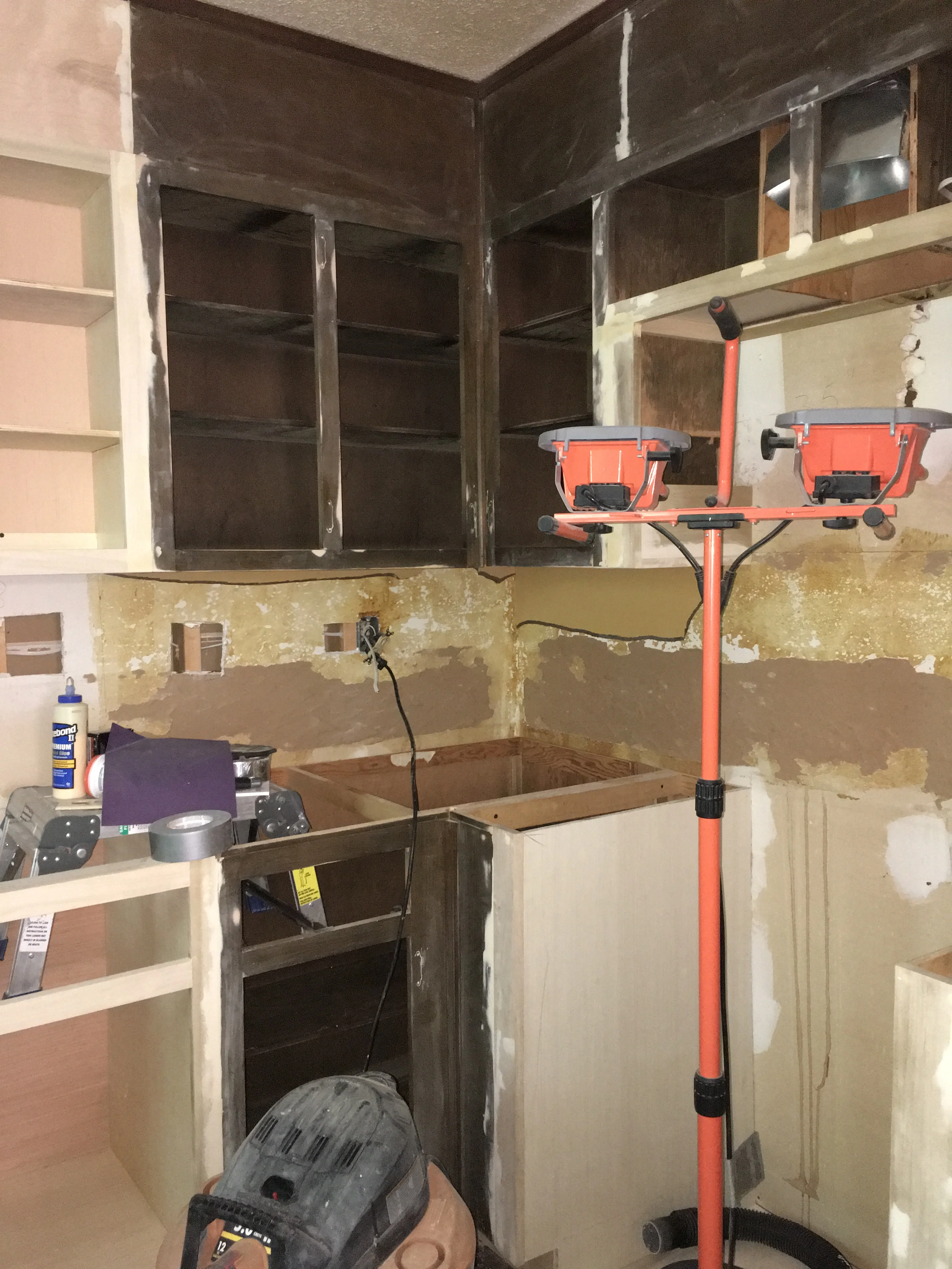 Kitchen remodeling project with exposed framing, drywall prep, and work lighting setup