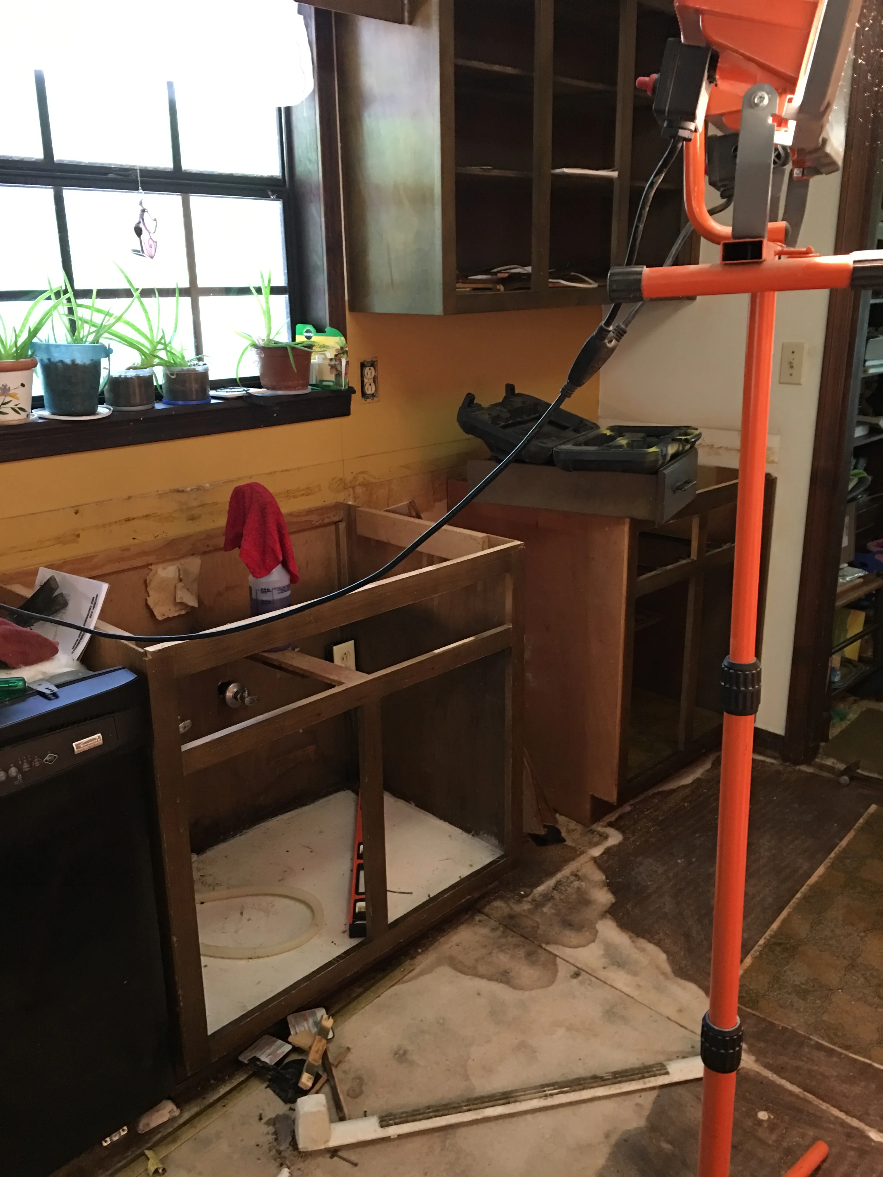 Kitchen remodel in progress showing wooden cabinetry frame and orange support beam installation
