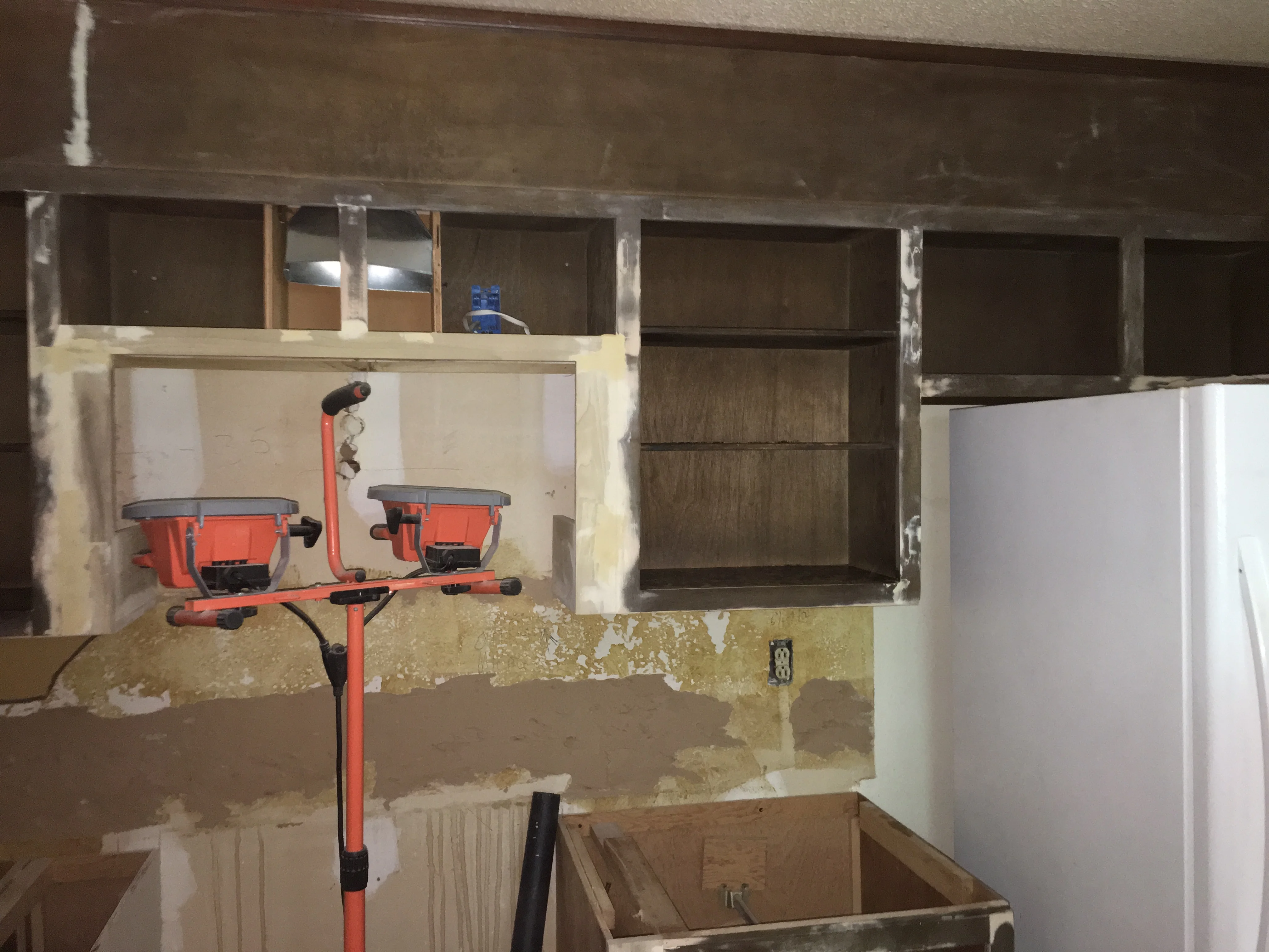 Kitchen remodel under construction with drywall, framing, and red work lights