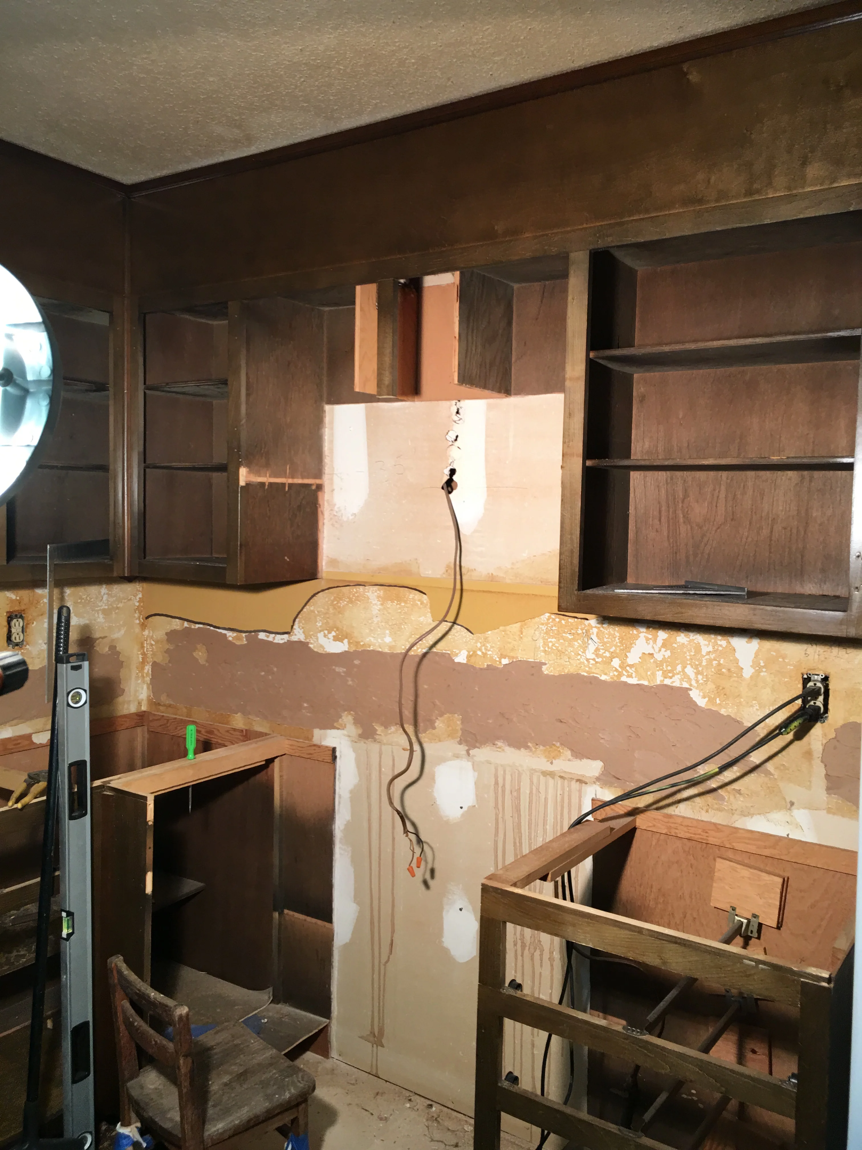 Kitchen remodel with drywall patches, wooden cabinet frames, and electrical wiring installed